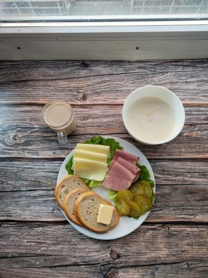 Zdjęcie przedstawia Dietę podstawową: Chleb mieszany pszenno-żytni Masło extra Szynka krucha z pieca wieprzowa, parzona Ser mozzarella Ogórek kiszony Sałata zielona Kawa zbożowa z mlekiem Woda mineralna Makaron na mleku